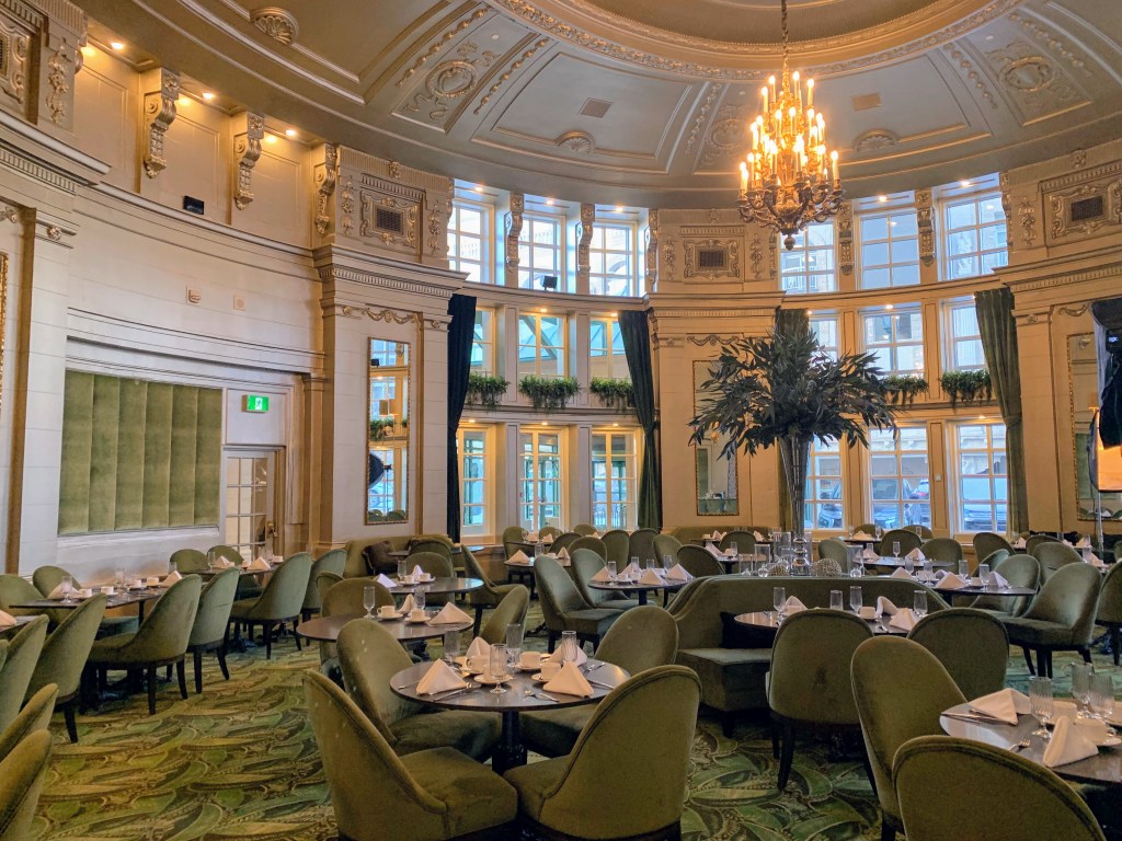 A domed dining room with a chandelier, tables and chairs.