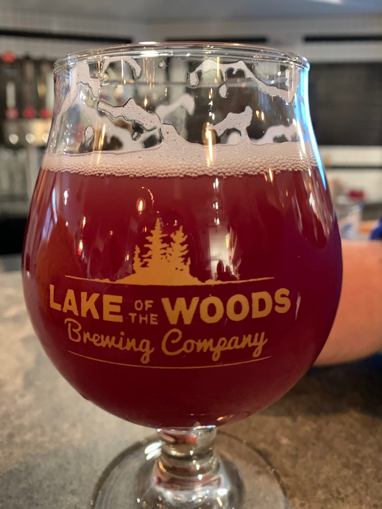 A glass of red beer in a glass that says Lake of the Woods Brewing Company on it.
